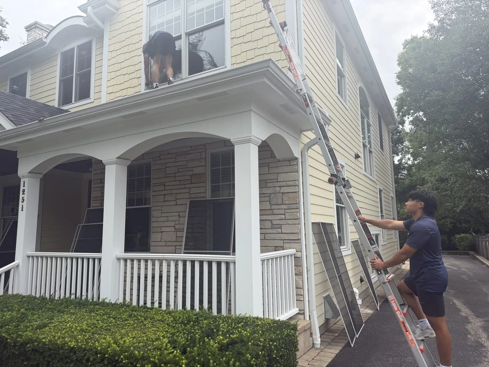 ClearDay technicians cleaning exterior windows on a yellow house