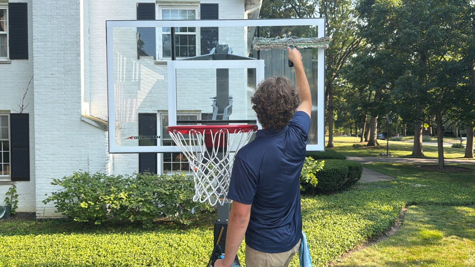 ClearDay technician scrubbing a glass basketball backboard