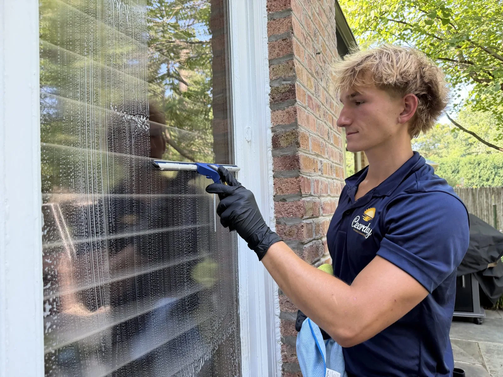 ClearDay technician scrubbing exterior windows during a residential window cleaning job