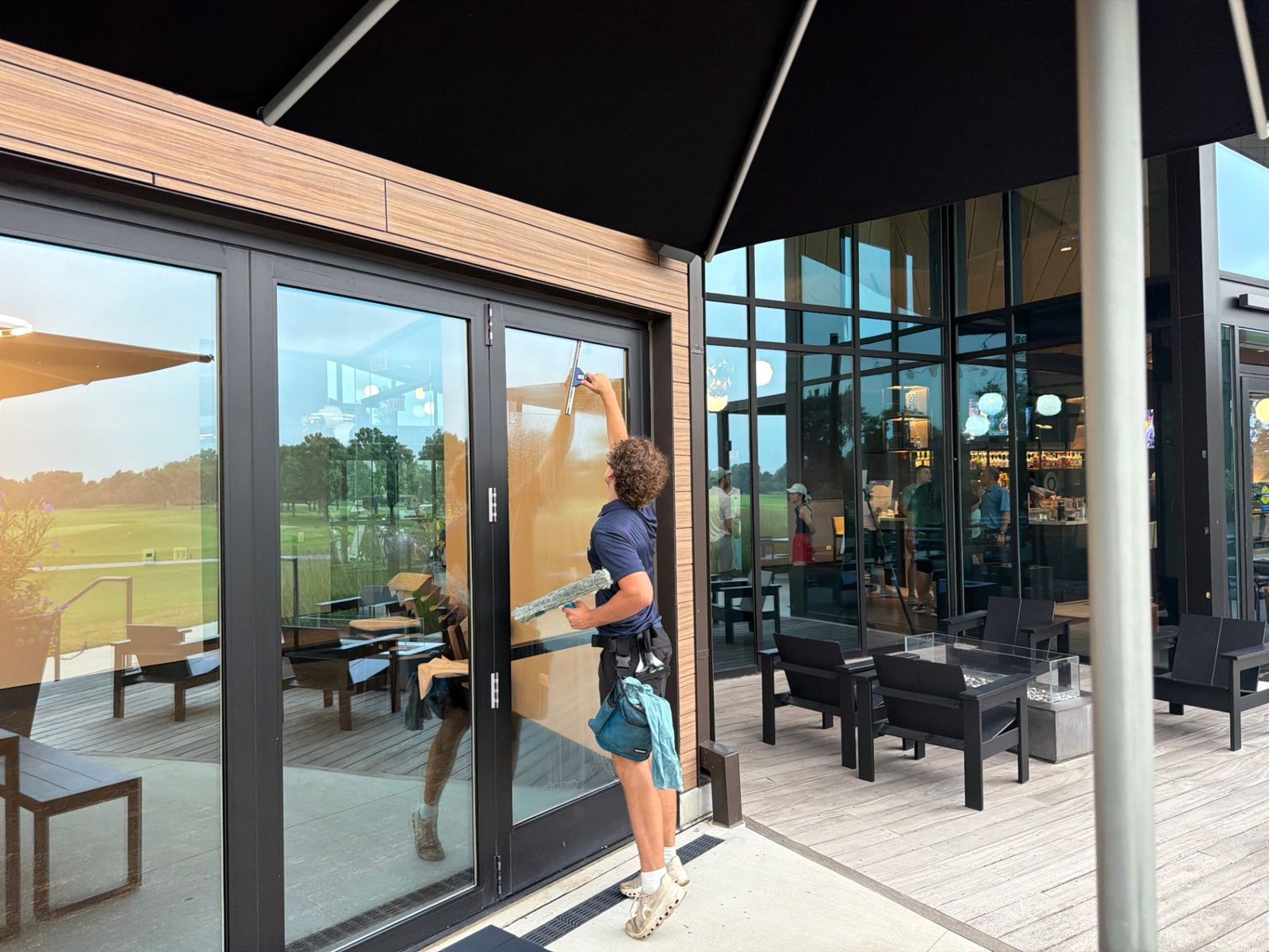 ClearDay technician squeegeeing exterior glass doors at a clubhouse patio
